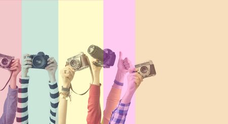 Different color hands holding cameras in front of colorful backgroundの写真素材