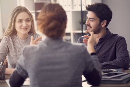 Young couple discussing with a female agent