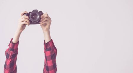 Young female, raised up arms and holding camera isolated backgroundの写真素材