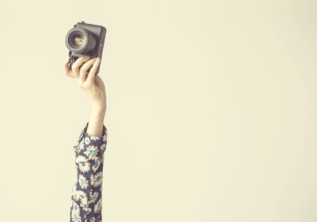 Female, arm lifted up and holding camera, isolated backgroundの写真素材