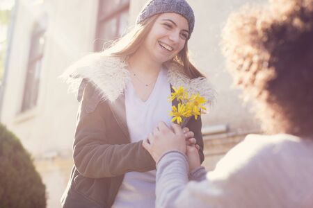 Young guy granting flower to his girlfriend in valentine dayの写真素材
