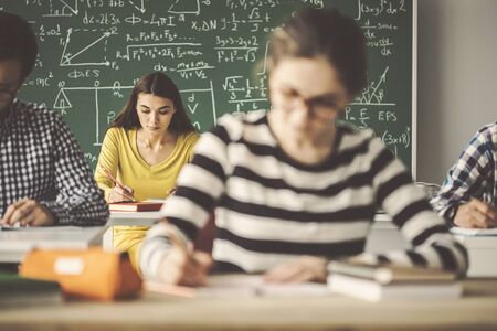 Students in classroom writing solving problemの写真素材
