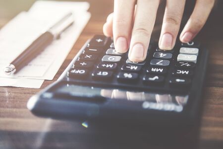 Person using calculator and counting billsの写真素材