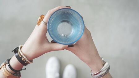 Woman hands holding blue glass of waterの写真素材