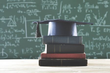 Stack books  graduate hat in front of  green chalkboardの写真素材