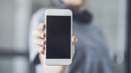 Woman holding and showing mobile phoneの写真素材