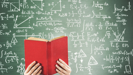 Reading book in front of green chalk board
