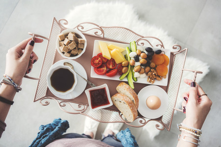 Delicious breakfast on tray carried by a young womanの写真素材