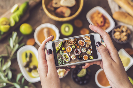 Woman taking a photo of breakfast tableの写真素材