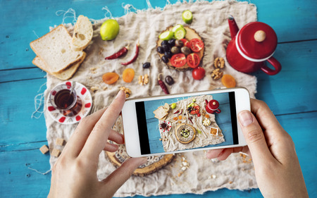Woman taking a photo of breakfast tableの写真素材