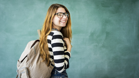 Happy student with backpack on green chalkboard
