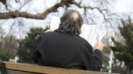 Old man reading newspaper in the parkの写真素材