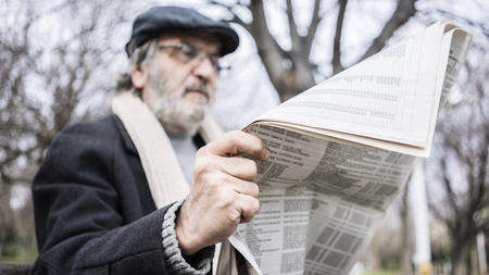Old man reading newspaper in the parkの写真素材