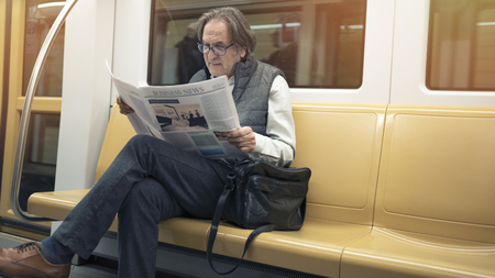 Man reading newspaper in the metro trainの写真素材