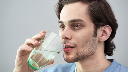 Young man drinking water on isolated backgroundの写真素材