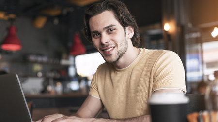 Young man using laptop computer in cafeの写真素材