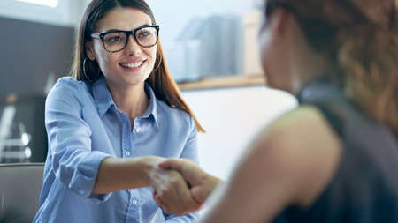 Women are shaking hands in officeの写真素材