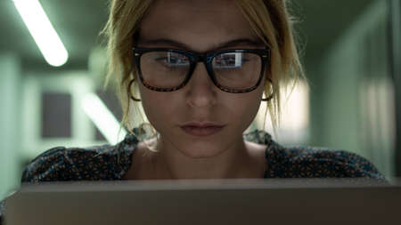 Woman using computer and computer screen light reflect from glassesの写真素材