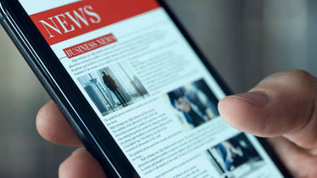 Reading news on mobile phoneの写真素材