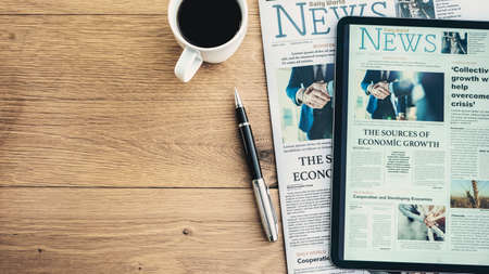Newspaper and digital tablet on wooden tableの写真素材