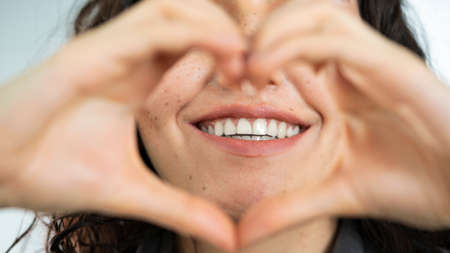 Woman smiling and making heart shape with her handsの写真素材