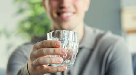 Young man drinks a glass of waterの写真素材