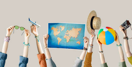 Many different arms raised up holding travel objectsの写真素材