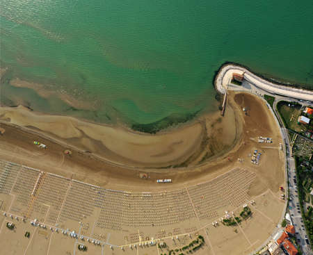 Umbrellas on the beach in Caorle in summer season aerial view from above