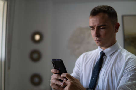 Young businessman reads a text message. Dresses in a suit and tie. The shirt is white and the tie is dark.の写真素材