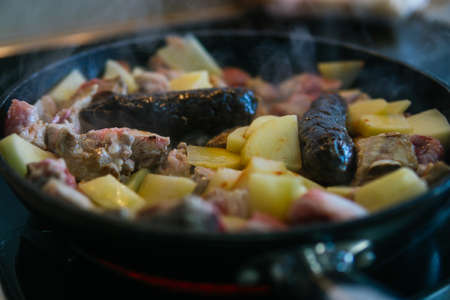 Frying pans preparing fried meat. Ingredients for the baked rice: Ribs, black pudding, bacon and sausage.の写真素材