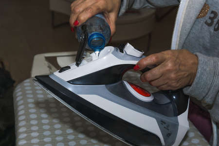 Unrecognizable woman filling the water of the ironing machineの写真素材