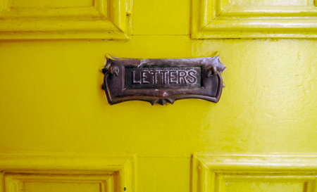 A quirky, vintage Art Nouveau Style "Letters" Mail Slot and it's bright yellow paneled door. Melbourne, Victoria, Australia 2015の写真素材