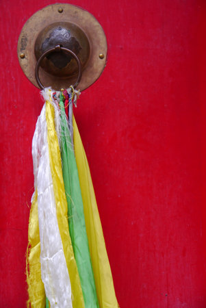 Visitors or worshippers sometimes add a prayer flag or piece of fabric to the door upon entering.の写真素材