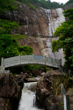Almost as spectacular as the waterfall itself, the Daixian River takes an exciting path into the Bangshang Village. This arched footbridge separates the falls from the river.の写真素材