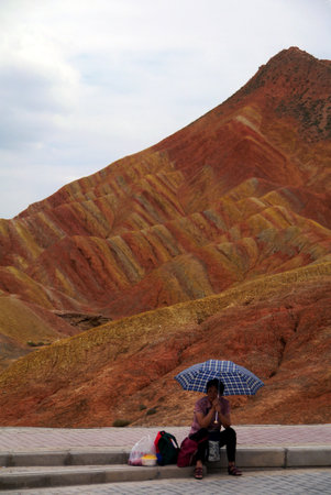 A visitor to the rainbow mountains finds shelter from the sun while she takes a lunch break.の写真素材