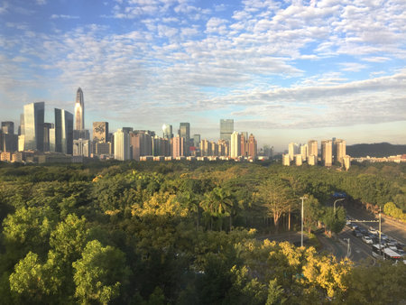 Just beyond a giant city park, the sun rises over the modern skyline of Shenzhen, China.の写真素材