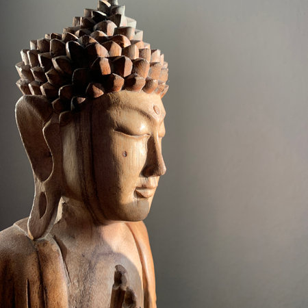 Morning sun shines on the face of a wooden buddha from Thailand.のeditorial素材