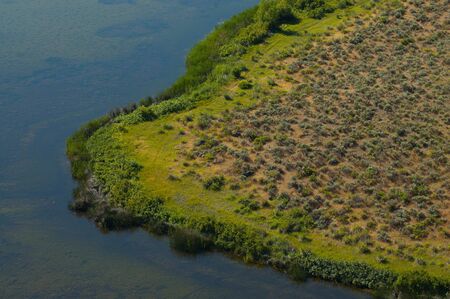 Beautifully curving wetland bend in a lake gives the illusion of a close up grassy viewの写真素材