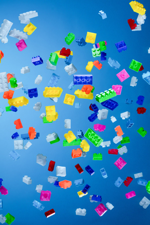 Pile of colored toy bricks falling on dark background.