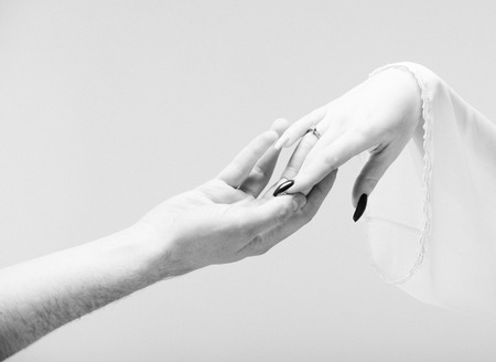 Hands of man and woman reaching to each other on gray background. Black and white photoの写真素材