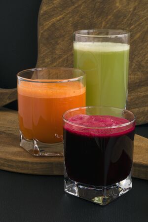 Vegetable juice in glass cups on a black background. Beets, celery, carrots.
の写真素材