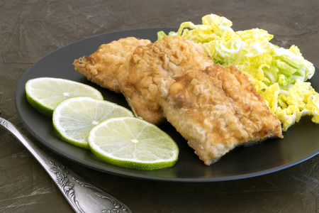 Fried fish with salad on a gray plate.