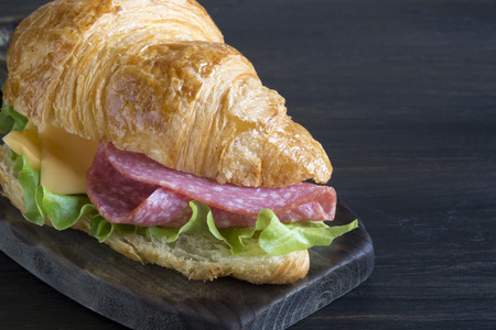 Croissant with sausage cheese and herbs. on dark backgroundの写真素材