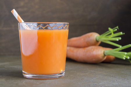 Juice of fresh ripe carrots on a brown background.の写真素材