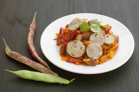 Stewed beans with vegetables and sausages. on black background.の写真素材