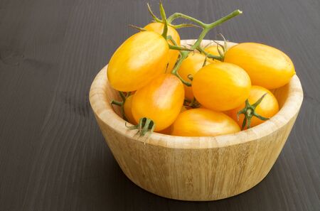 yellow tomatoes on a wooden Board. black backgroundの写真素材