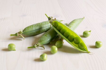 Young green peas on white wooden background.の写真素材