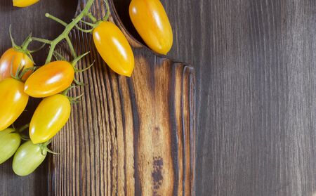 yellow tomatoes on a wooden Board. black backgroundの写真素材