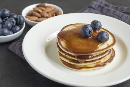 pancakes with syrup nuts and blueberries. on a white plateの写真素材