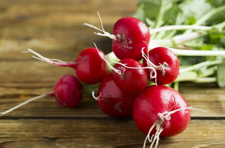 a bunch of ripe red radishes on a wooden background. summer harvest of red radishesの写真素材